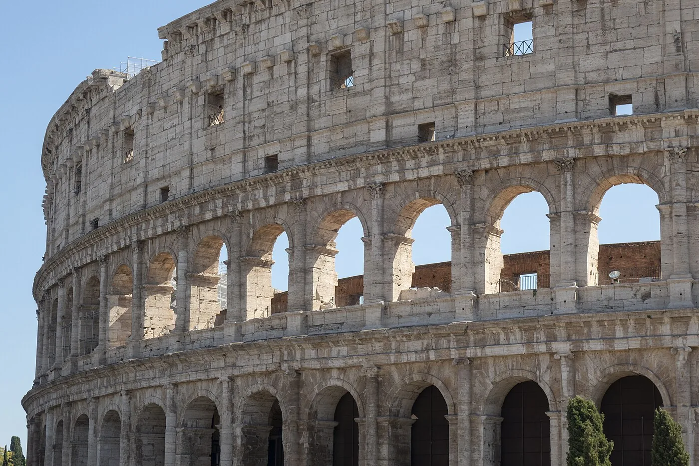 ローマのコロッセオの外壁の実写。青空を背景に何層ものアーチが連なる